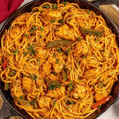 Amazing Cajun Chicken Pasta in 30 Minutes 3 Delicious Cajun Chicken Pasta served hot in a rustic black cast-iron skillet, garnished with fresh parsley and green peppers.