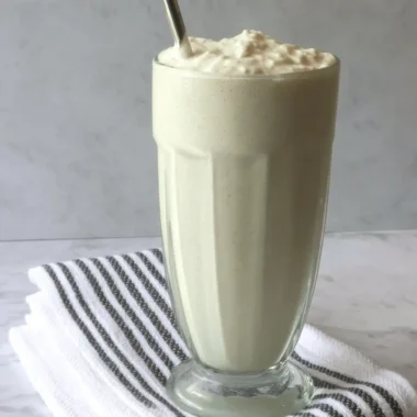 Ultimate Homemade Vanilla Bean Frappuccino Recipe 4 Close-up of a thick, creamy beverage made using the vanilla bean frappuccino recipe, served in a tall, ridged glass with a metal straw.