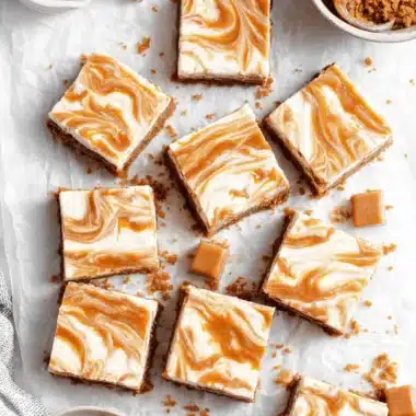 Irresistibly Easy Golden Oreo Strawberry Cheesecake Bars 3 Decadent, creamy golden oreo strawberry cheesecake bars displayed on parchment paper, featuring a thick crumb crust and a luxurious swirl topping.