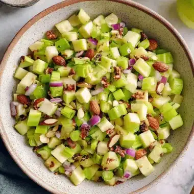Amazing Celery Salad: Quick & Easy Recipe 4 Crisp celery salad featuring diced green apples, red onion, and whole almonds in a speckled ceramic bowl.