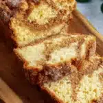 Amazing Easy Amish Cinnamon Bread Recipe 6 Sliced loaf of freshly baked amish cinnamon bread dusted with sugar on a rustic wooden board.