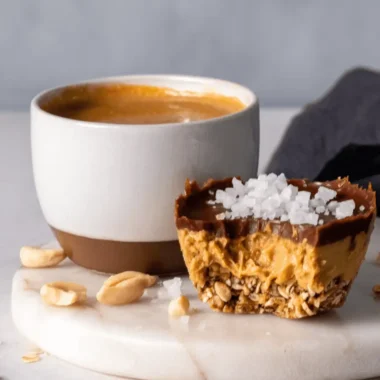 Amazing Foolproof No Bake Peanut Butter Oat Cups 4 Close-up of a single bitten no bake peanut butter oat cup topped with sea salt, presented next to a coffee mug.