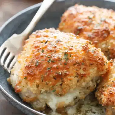 Easy Cheddar Ranch Chicken: A Weeknight Victory 4 Golden-brown, breaded cheddar ranch chicken thighs stuffed with melted cheese and herbs, served in a rustic dark bowl.