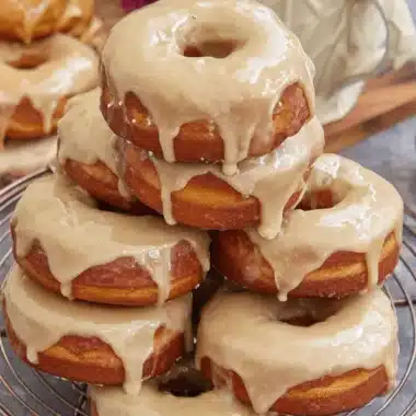 Foolproof Homemade Maple Donut Bars 4 Close-up of stacked, maple-glazed donuts that resemble tasty maple donut bars cooling on a copper rack.