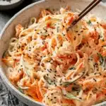 Vibrant Kani Salad Recipe: Quick & Easy Perfection 6 Eye-level close-up of a fresh kani salad recipe in a rustic bowl, tossed with vegetables and lifted by wooden chopsticks.