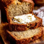 Amazing Sour Cream Banana Bread Recipe 5 Sliced loaf of warm sour cream banana bread on a rustic wooden board with melting butter.