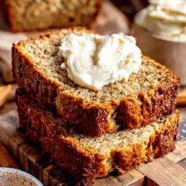 Amazing Sour Cream Banana Bread Recipe 3 Delicious slices of moist sour cream banana bread with creamy butter on a rustic cutting board.