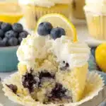 Ultimate Lemon Blueberry Cupcakes: Easy & Delicious 5 Close-up of a delectable Lemon Blueberry Cupcake with a bite taken out, featuring creamy frosting, fresh blueberries, and a lemon slice.