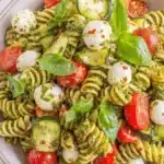 The Ultimate Pesto Pasta Salad Recipe 5 Vibrant pesto pasta salad with fusilli, cherry tomatoes, zucchini, and mozzarella in a ceramic bowl.