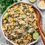 Ultimate Mexican Street Corn Pasta Salad 6 A vibrant mexican street corn pasta salad with farfalle, black beans, corn, avocado, cotija cheese, and cilantro in a white bowl on marble.