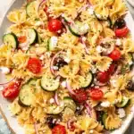 Vibrant Mediterranean Pasta Salad: Easy & Fresh 5 A vibrant, close-up overhead view of a fresh mediterranean pasta salad with farfalle, cherry tomatoes, cucumbers, feta, and olives in a light bowl.