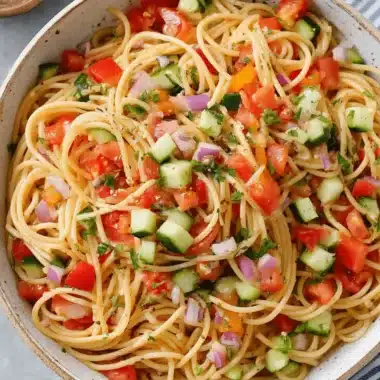 Amazing Spaghetti Pasta Salad: Simple & Flavorful 3 Vibrant spaghetti pasta salad with fresh tomatoes, cucumber, red onion, and herbs in a rustic bowl.