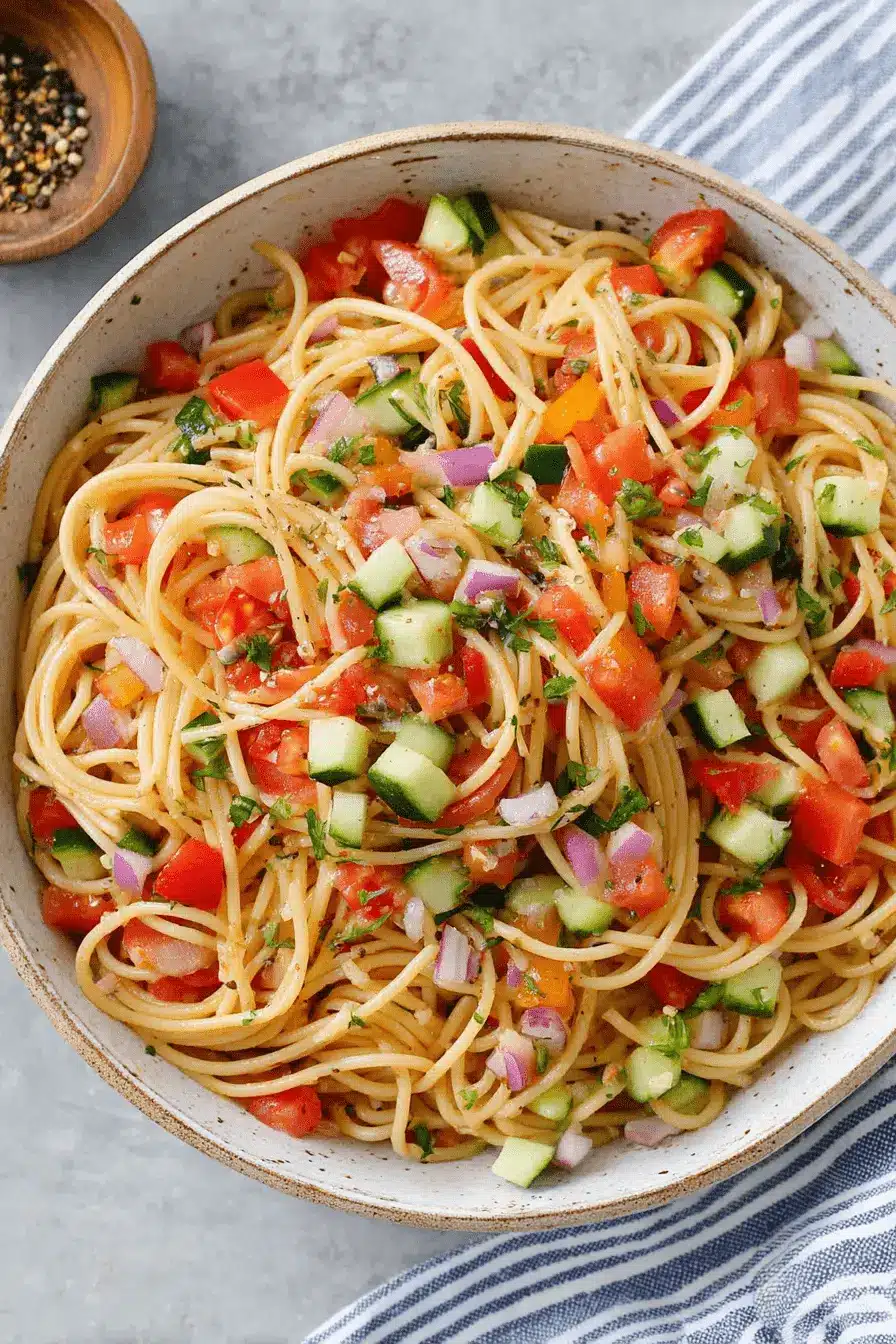 Amazing Spaghetti Pasta Salad: Simple & Flavorful 2 Vibrant spaghetti pasta salad with fresh tomatoes, cucumber, red onion, and herbs in a rustic bowl.