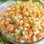 Foolproof Creamy Hawaiian Pasta Salad 8 Close-up of a vibrant hawaiian pasta salad in a glass bowl, featuring creamy macaroni, shredded carrots, and green onions.
