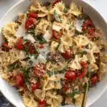 Amazing Bruschetta Pasta Salad: Simple & Fresh 9 Vibrant farfalle bruschetta pasta salad with cherry tomatoes, basil, and Parmesan in a white bowl.