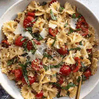 Amazing Bruschetta Pasta Salad: Simple & Fresh 3 Vibrant farfalle bruschetta pasta salad with cherry tomatoes, basil, and Parmesan in a white bowl.