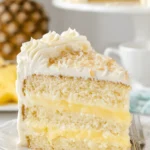Amazing Pineapple Coconut Cake: Tropical Escape 6 Slice of layered pineapple coconut cake with creamy pineapple filling, white frosting, and toasted coconut flakes.