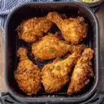 Amazing Air Fryer Fried Chicken Recipe 9 Golden-brown, crispy air fryer fried chicken drumsticks served in a black basket with a side of creamy coleslaw on a wooden table.