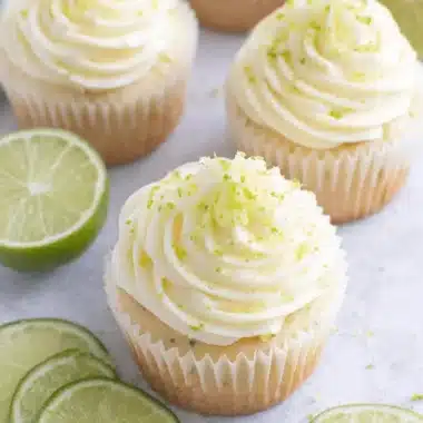 Ultimate Key Lime Cupcakes: Easy & Zesty Recipe 4 Four fluffy key lime cupcakes with creamy white frosting and fresh lime zest, photographed from an overhead perspective.