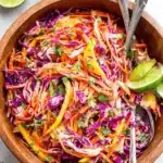 Vibrant Mango Slaw: Your New Go-To Side 7 Rustic wooden bowl filled with vibrant, creamy mango slaw, shredded cabbage, and fresh lime accents.