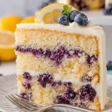 Ultimate Lemon Blueberry Cake: So Moist & Easy! 4 Close-up of a perfectly sliced Lemon Blueberry Cake garnished with mint and a fresh lemon slice.