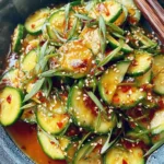 Amazing Asian Cucumber Salad: Quick & Easy 5 Close-up overhead shot of a vibrant asian cucumber salad garnished with sesame seeds and scallions in a rustic blue ceramic bowl.