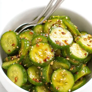 Vibrant Japanese Cucumber Salad Recipe 3 Overhead view of fresh japanese cucumber salad with sesame seeds, red chili flakes, and a golden dressing in a white bowl.