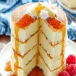 Easy Fluffy Japanese Soufflé Pancakes 8 Towering stack of four fluffy japanese souffle pancakes drizzled generously with golden syrup and garnished with fresh raspberries.