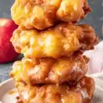 Amazing Baked Apple Fritter Bites Recipe 5 Stack of four golden-brown Apple Fritter Bites generously drizzled with thick, glossy caramel sauce.