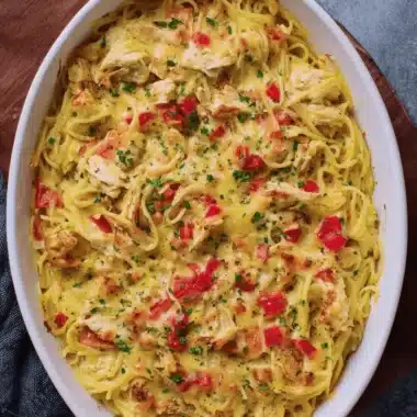 Amazing Easy Chicken Spaghetti Casserole 4 Cheesy, baked chicken spaghetti casserole topped with melted cheese and fresh parsley, served in a white oval dish.