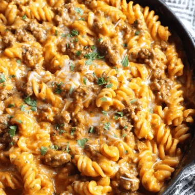 Amazing One-Pot Creamy Beef Pasta Recipe 3 Hearty cast iron skillet filled with garnished rotini Creamy Beef Pasta, viewed from overhead.