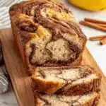 Ultimate Foolproof Cinnamon Swirl Banana Bread 8 Sliced loaf of moist cinnamon swirl banana bread on a wooden cutting board, revealing the inner swirl pattern.