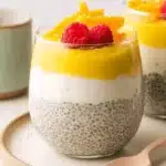 Vibrant Lemon Curd Chia Pudding: A Quick Recipe 6 Layered lemon curd chia pudding dessert in a clear glass, garnished with fresh raspberries and candied orange peel.