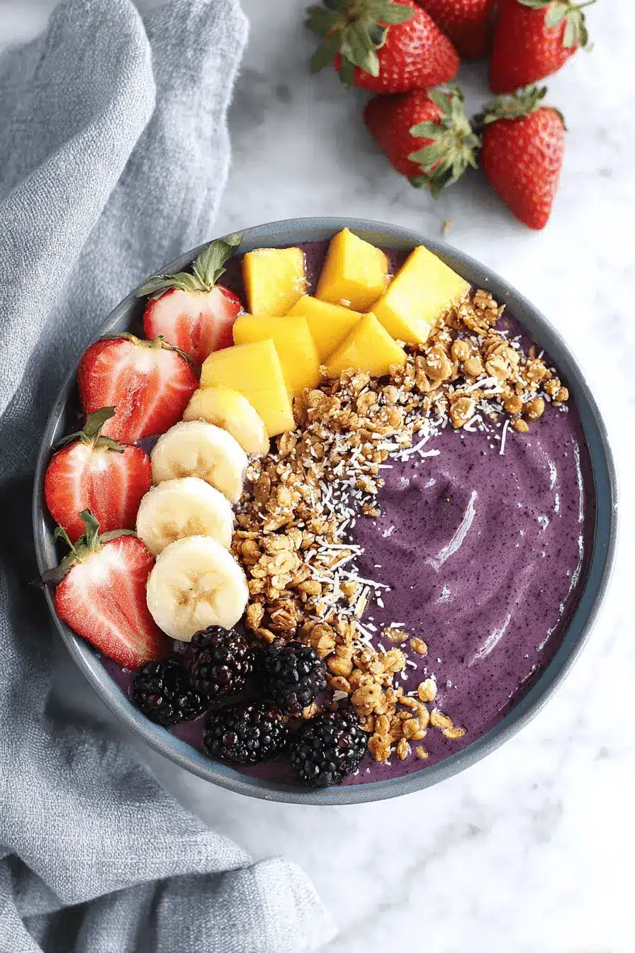 Ultimate Acai Bowl Recipe: Thick, Creamy, & Easy 2 Overhead view of a vibrant acai bowl topped with fresh strawberries, bananas, mango, and granola, illustrating a delicious acai bowl recipe.