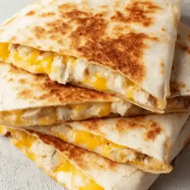 The Ultimate Taco Bell Chicken Quesadilla 3 Close-up of golden brown Taco Bell Chicken Quesadilla wedges, generously filled with shredded chicken and melted cheese.