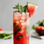 Vibrant Watermelon Mojito: Easy & Refreshing 7 A vibrant watermelon mojito in a frosted glass with fresh mint and a watermelon slice on a marble counter.
