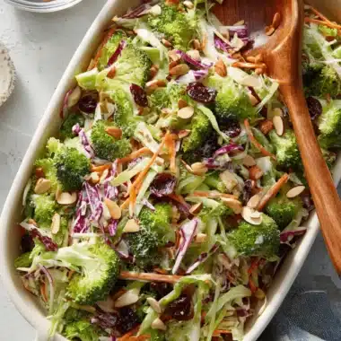 Amazing Broccoli Slaw: Quick & Easy Recipe 3 Close-up of vibrant creamy Broccoli Slaw with cranberries, almonds, red cabbage, and carrots in a ceramic dish.