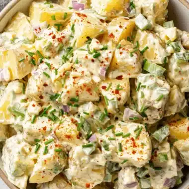 The Ultimate Potato Salad with Egg: Foolproof Recipe 4 Close-up of creamy potato salad with egg, garnished with chives and paprika in a rustic earthenware bowl.