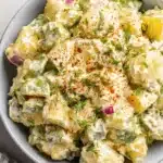 Amazing Potato Salad with Egg: A Creamy Classic 5 Creamy homemade potato salad with egg, fresh dill, and paprika in a light blue-grey ceramic bowl.