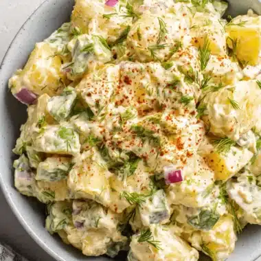 Amazing Potato Salad with Egg: A Creamy Classic 4 Creamy homemade potato salad with egg, fresh dill, and paprika in a light blue-grey ceramic bowl.