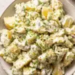 Amazing Potato Salad with Egg Recipe 9 Close-up of a rustic bowl of creamy homemade potato salad with egg, garnished with chives and red pepper flakes.