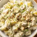 Ultimate Potato Salad with Egg: Creamy & Easy 8 Close-up of creamy homemade potato salad with egg in a rustic ceramic bowl, garnished with paprika and fresh herbs.