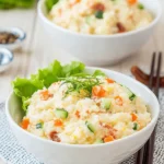 The Ultimate Japanese Potato Salad Recipe 6 Creamy Japanese potato salad with carrots, cucumber, and chives, served in a white bowl with chopsticks.