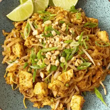 Amazing Easy Chicken Pad Thai Recipe 4 Close-up overhead view of a vibrant chicken pad thai recipe served in a teal bowl, garnished with lime, peanuts, and scallions.