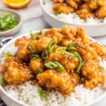The Ultimate Panda Express Orange Chicken Recipe 5 Two bowls of delicious Panda Express orange chicken served over white rice, garnished with green onions and fresh orange slices.