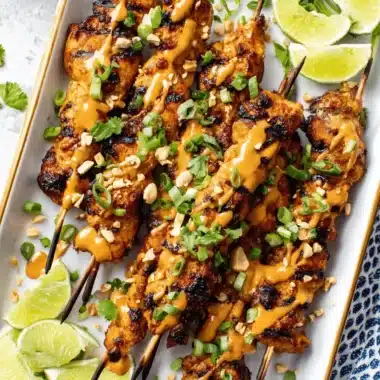 The Ultimate Chicken Satay Recipe for Any Cook 3 Golden brown grilled chicken satay skewers with creamy peanut sauce, fresh lime, and cilantro, inspiring your next chicken satay recipe.