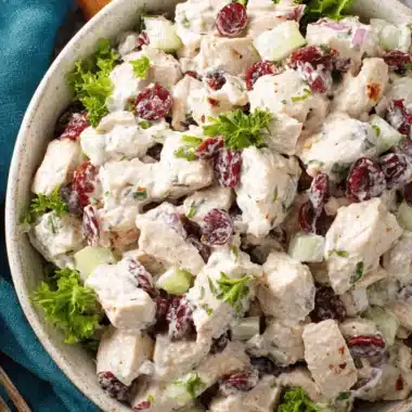Wonderful Canned Chicken Salad: Fast & Easy Lunch 4 A creamy bowl of fresh canned chicken salad with dried cranberries, cucumber, and green herbs on a dark surface, ready to eat.