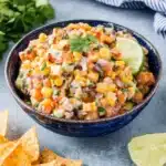 The Ultimate Cowboy Caviar Creamy Dip 5 Close-up of vibrant cowboy caviar creamy salsa in a blue bowl, garnished with lime and cilantro.