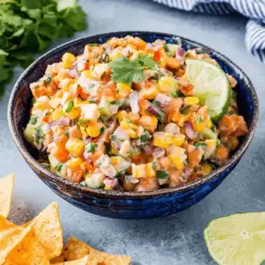 The Ultimate Cowboy Caviar Creamy Dip 4 Close-up of vibrant cowboy caviar creamy salsa in a blue bowl, garnished with lime and cilantro.