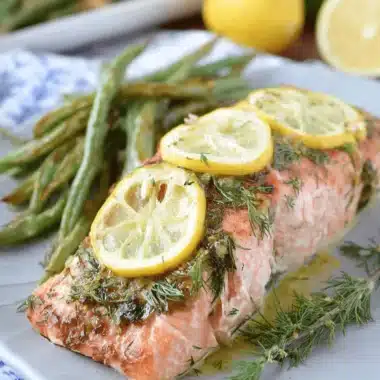 Ultimate Lemon Herb Salmon: Quick & Easy Dinner 3 Beautifully baked lemon herb salmon fillet garnished with fresh dill and lemon slices, served with roasted green beans.